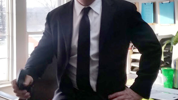 A man in a suit and tie sitting on top of a desk.
