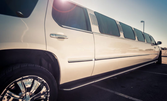 A white limo is parked in the parking lot.