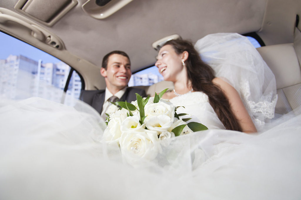 A bride and groom in the back of a limo.