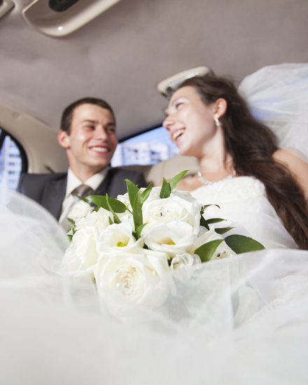 A bride and groom in the back of a limo.