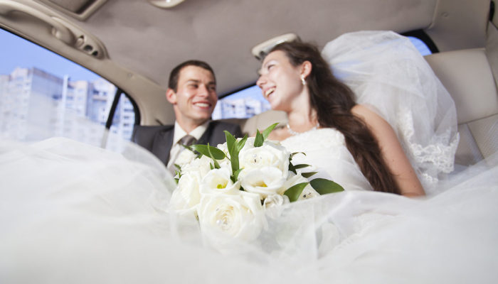A bride and groom in the back of a limo.