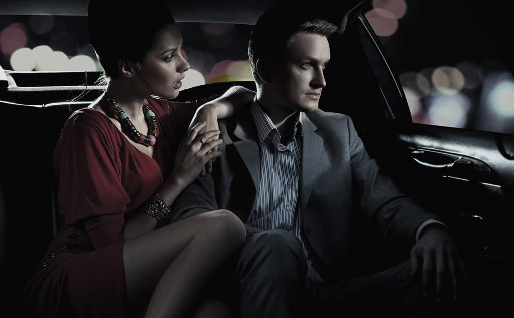 A man and woman sitting in the back of a car.