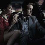 A man and woman sitting in the back of a car.