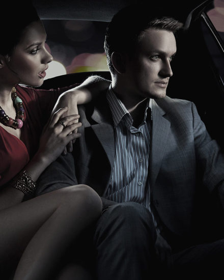 A man and woman sitting in the back of a car.