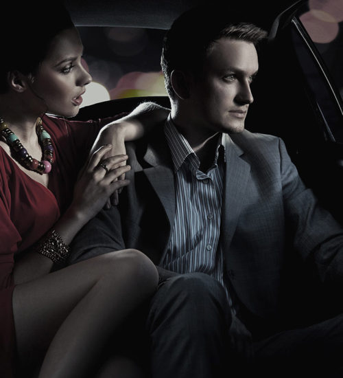 A man and woman sitting in the back of a car.