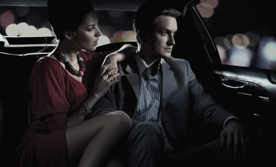 A man and woman sitting in the back of a car.