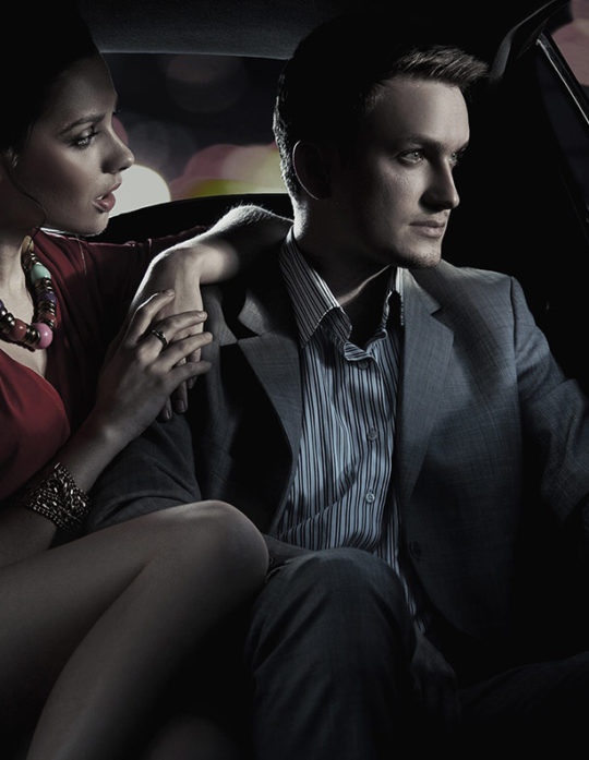 A man and woman sitting in the back of a car.