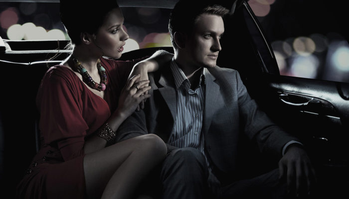 A man and woman sitting in the back of a car.